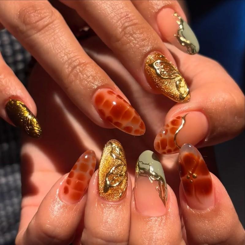 A closeup of hands with elaborately designed nails featuring textured patterns and metallic accents - مدل ناخن مخملی