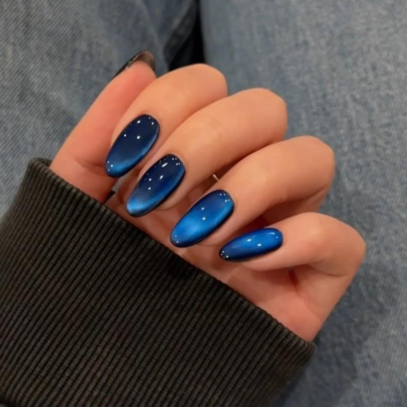 A hand with nails painted in a glossy design resembling blue sapphire - مدل ناخن مخملی