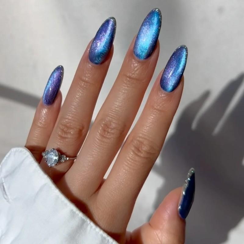 A hand with metallic blue-purple velvet manicure and a ring with a gemstone visible - مدل ناخن مخملی