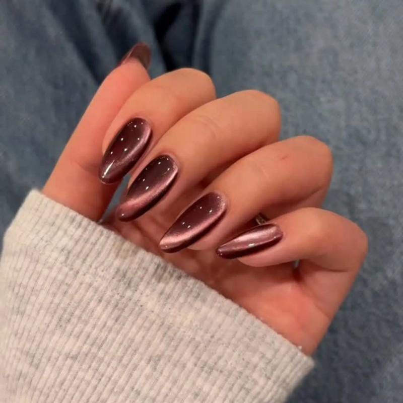 A hand displaying plum-toned metallic manicured nails with a glossy finish and small decorative dots - مدل ناخن مخملی