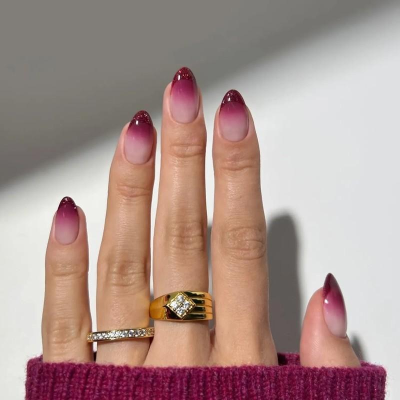 Hand with burgundy ombre nails and two rings including a gold one with a diamond, مدل ناخن کوتاه پاییزی اومبره زرشکی
