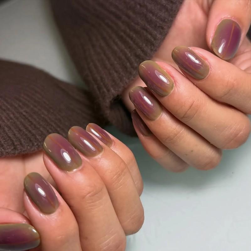 Closeup of hands with well-manicured fingernails in a glossy finish, مدل ناخن کوتاه پاییزی هاله ای زیتونی