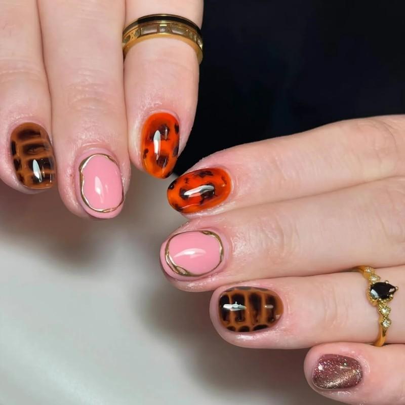 Hands with nail art featuring tortoiseshell patterns and metallic accents wearing gold rings, مدل ناخن کوتاه پاییزی کروکودیل و لاک پشتی
